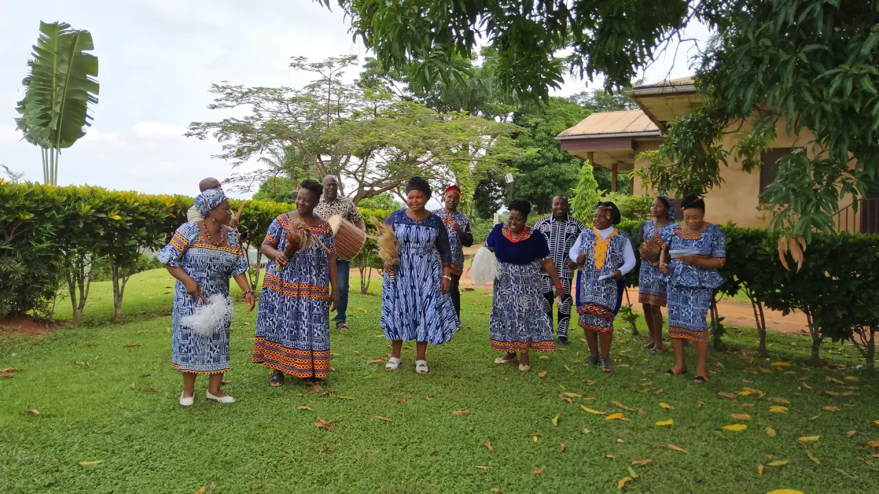 Members of the Psalms That Sing team walking across a lawn in matching blue-and-white print, singing, with a drum, feather fans and rattles