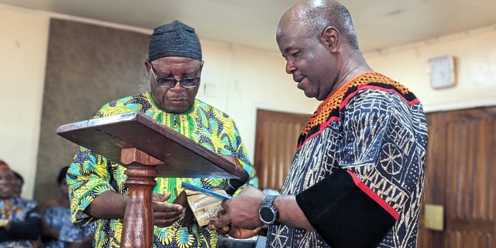 Mr. Atah Davidson receiving a copy of the Kom Psalms booklet